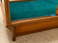 Load image into Gallery viewer, Close-up of a wooden display case or cabinet with a teal green velvet interior lining, resting on a beige carpet.