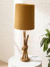 Load image into Gallery viewer, Vintage table lamp with sculptural curved wood base and tall brown woven-texture shade illuminated with a warm glow