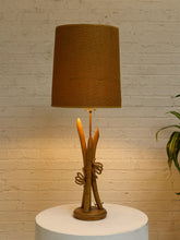 Load image into Gallery viewer, Vintage table lamp with sculptural curved wood base and tall brown woven-texture shade illuminated with a warm glow