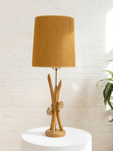 Load image into Gallery viewer, Vintage table lamp with sculptural curved wood base and tall brown woven-texture shade illuminated with a warm glow