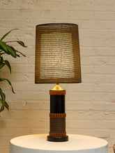Load image into Gallery viewer, Vintage table lamp with tall brown woven shade, black cylindrical base, warm wood accents, and wrapped textured detailing