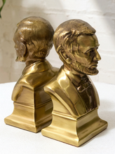 Load image into Gallery viewer, A pair of metallic gold bust bookends shaped like Abraham Lincoln, shown from front and side angles on a white surface against a white brick wall background.