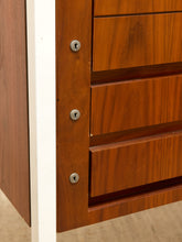 Load image into Gallery viewer, Close-up of a reddish-brown wooden drawer unit with three visible silver keyholes on the front edge and a white vertical trim strip beside it.