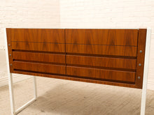 Load image into Gallery viewer, A mid-century modern wooden credenza or sideboard with six drawers, featuring a rich walnut wood grain finish and a white metal frame, set against a white brick wall and light carpet.