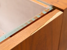 Load image into Gallery viewer, Close-up of a wooden cabinet or display case with a glass top, showing the wood grain, edge trim, and a visible crack in the glass.