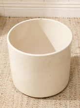Load image into Gallery viewer, An off-white ceramic planter pot with a textured matte finish, sitting on a woven jute rug.