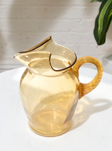Load image into Gallery viewer, Vintage translucent amber glass pitcher with rounded body, freeform pouring rim, sculptural spout, and large ribbed loop handle