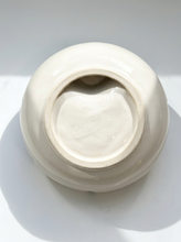 Load image into Gallery viewer, A glossy off-white ceramic vase viewed from underneath, showing its circular base and center opening, set against a plain white background with soft shadows.