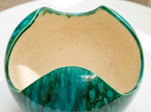 Load image into Gallery viewer, A close-up of a ceramic bowl with a glossy teal and green marbled exterior and a warm beige interior, shown on a white surface.
