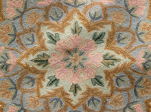 Load image into Gallery viewer, A close-up of a textured area rug featuring a detailed, symmetrical floral and geometric medallion pattern in dusty pink, ochre brown, sage green, and light blue-gray.