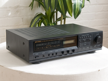 Load image into Gallery viewer, Vintage black Optimus AM/FM stereo receiver with rectangular digital tuner display, large volume knob, front control buttons, and vented top panel
