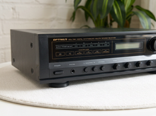 Load image into Gallery viewer, Vintage black Optimus AM/FM stereo receiver with rectangular digital tuner display, large volume knob, front control buttons, and vented top panel