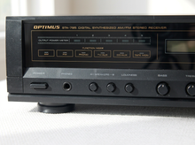 Load image into Gallery viewer, Vintage black Optimus AM/FM stereo receiver with rectangular digital tuner display, large volume knob, front control buttons, and vented top panel