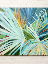 Load image into Gallery viewer, Image 2 of 8: A colorful abstract painting of tropical palm leaves in shades of blue, green, yellow, and orange, displayed on a white brick wall.