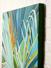 Load image into Gallery viewer, Image 6 of 8: A square canvas wall art print featuring an abstract botanical design with layered leaves in shades of teal, blue, green, yellow, and white, shown hanging against a white brick wall.