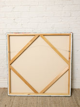Load image into Gallery viewer, Image 8 of 8: The back of a large square canvas painting, showing a light wood gallery frame and support structure, leaning against a white painted brick wall on a textured beige rug.