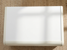 Load image into Gallery viewer, A white rectangular box or case with rounded corners, photographed from above on a textured beige woven surface. Soft shadows cross the lid.
