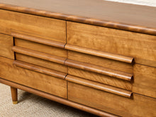 Load image into Gallery viewer, Image 8 of 16: Close-up of a mid-century modern wooden sideboard or dresser with six drawers, featuring curved cylindrical pulls and a warm honey-toned wood finish.