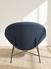 Load image into Gallery viewer, Image 6 of 17: A modern upholstered chair with a rounded, dome-shaped navy blue fabric seat and black metal legs, set against a white brick wall on a light beige rug.