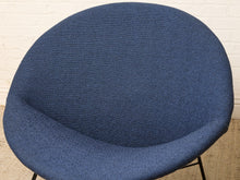 Load image into Gallery viewer, Image 7 of 17: A close-up of a modern round upholstered chair in textured blue fabric, showing the seat and curved backrest against a white brick wall background.