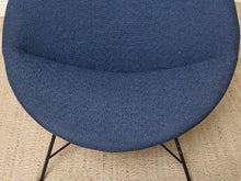 Load image into Gallery viewer, Image 9 of 17: A close-up of a modern round upholstered chair with a textured blue fabric seat and black metal legs, set on a beige woven rug.