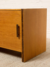 Load image into Gallery viewer, Image 10 of 17: Vintage mid-century modern rectangular wooden cabinet featuring a honey-brown wood grain finish, single flat-panel door, dark vertical metal pull, and contrasting darker wood trim along both sides.
