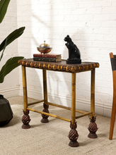 Load image into Gallery viewer, Image 2 of 20: Antique rectangular bamboo-style accent table featuring a dark brown embossed decorative tabletop, ornate gold-tone floral trim, slender golden bamboo legs, crossbar supports, and sculptural pineapple-like feet.
