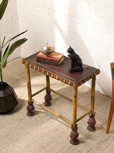 Load image into Gallery viewer, Image 3 of 20: Antique rectangular bamboo-style accent table featuring a dark brown embossed decorative tabletop, ornate gold-tone floral trim, slender golden bamboo legs, crossbar supports, and sculptural pineapple-like feet.