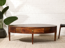 Load image into Gallery viewer, Image 1 of 16: Vintage elongated oval wooden coffee table featuring a dark brown wood finish, gently curved apron, single front storage drawer with a round metal knob, slender tapered legs, and visible surface wear.