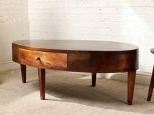 Load image into Gallery viewer, Image 2 of 16: Vintage elongated oval wooden coffee table featuring a dark brown wood finish, gently curved apron, single front storage drawer with a round metal knob, slender tapered legs, and visible surface wear.