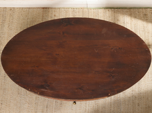 Load image into Gallery viewer, Image 4 of 16: Vintage elongated oval wooden coffee table featuring a dark brown wood finish, gently curved apron, single front storage drawer with a round metal knob, slender tapered legs, and visible surface wear.