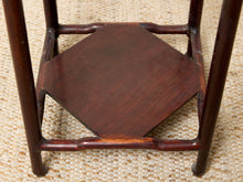 Load image into Gallery viewer, Image 14 of 16: Close-up of the dark reddish-brown wooden base and octagonal seat of a traditional Chinese chair on a woven straw mat.