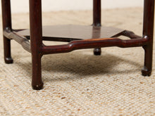 Load image into Gallery viewer, Image 15 of 16: Close-up of a dark reddish-brown wooden table leg and lower shelf on a woven beige rug.