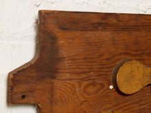 Load image into Gallery viewer, Image 4 of 9: A close-up of a rustic wooden board or plaque with a warm medium-brown finish, showing visible wood grain, a small round peg hole, and a circular cutout on the right side against a white textured wall.