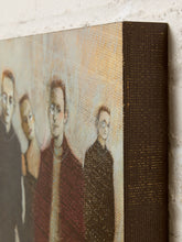 Load image into Gallery viewer, Image 6 of 9: A close-up of a textured canvas or print showing a stylized portrait of four people, with a dark brown spine edge visible against a white brick wall background.
