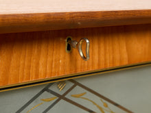 Load image into Gallery viewer, Image 20 of 27: Close-up of a wooden furniture piece showing a warm honey-toned wood grain surface, a brass keyhole, and part of a patterned surface below.