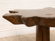 Load image into Gallery viewer, Image 10 of 16: Close-up of a rustic dark brown wooden table with a natural irregularly shaped top and a thick cylindrical leg, set against a white brick wall and light beige rug.