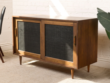Load image into Gallery viewer, Image 5 of 24: Vintage wooden credenza with two black textured sliding cabinet doors, warm brown wood frame, gold-tone hardware, and short tapered legs