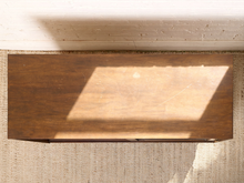 Load image into Gallery viewer, Image 7 of 24: Vintage wooden credenza with two black textured sliding cabinet doors, warm brown wood frame, gold-tone hardware, and short tapered legs