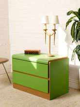 Load image into Gallery viewer, Image 2 of 16: Vintage 1970s postmodern nightstand featuring bright lime-green drawer fronts, contrasting gold-tone trim, a gently rounded top, and two handle-free drawers.
