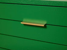 Load image into Gallery viewer, Image 10 of 15: A close-up of a modern, minimalist rectangular drawer pull handle in a brushed gold finish, mounted on a vibrant green wooden drawer with horizontal slats.