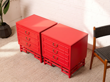 Load image into Gallery viewer, Image 3 of 21: Pair of vintage 1960s Hollywood Regency nightstands featuring vibrant poppy red painted finishes, three drawers each with brass-tone curved handles, decorative faux bamboo trim, and sculptural bamboo-inspired bases.