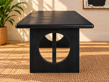 Load image into Gallery viewer, Sylvia dining table in Charcoal with rectangular rounded-edge top and sculptural black fluted pedestal bases with circular cutouts.