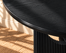 Load image into Gallery viewer, Sylvia round dining table in Charcoal with black oak veneer finish, fluted pedestal base, and distinctive circular cutouts.