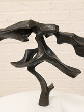 Load image into Gallery viewer, Abstract black metal sculpture with organic, branch-like curves standing on a white pedestal against a white brick wall background.