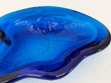 Load image into Gallery viewer, A translucent blue glass dish with an organic, wavy shape, photographed close-up on a white textured background.