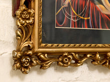 Load image into Gallery viewer, Close-up of an ornate gold picture frame with carved floral details, mounted on a white painted brick wall. A portion of the framed artwork is visible, showing red draped fabric and dark background tones.