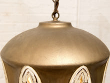 Load image into Gallery viewer, Close-up of a vintage-style hanging lantern with a warm brass or bronze metal body, featuring decorative white and gold cutout panels near the bottom and a hanging chain at the top.