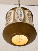 Load image into Gallery viewer, A vintage-style brass pendant light with ornate cutout patterns on a white brick wall background.