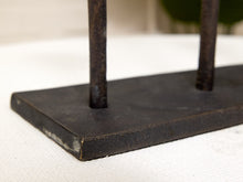 Load image into Gallery viewer, Close-up of a dark metal stand with a rectangular base and two vertical bars, resting on a white textured surface.